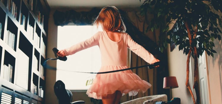 girl dancing in a room with bookshelves and an indoor tree near a window