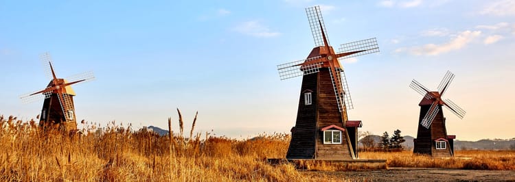 three old windmills in a field of brown grasses