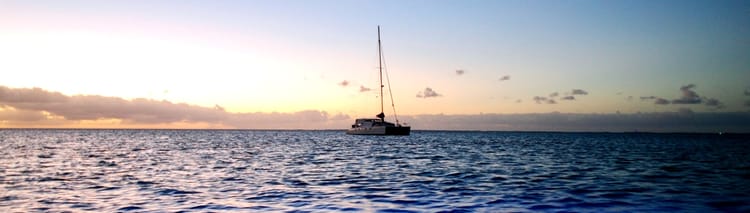 catamaran at sea beneath a sunset sky