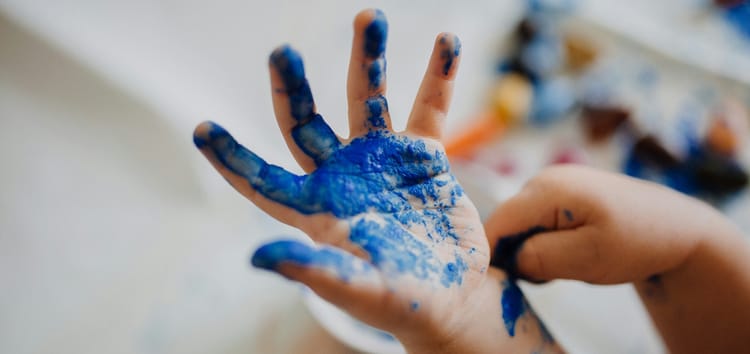 child’s hand covered in blue fingerpaint