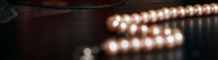 a blurred string of pearls lying on a table of dark wood