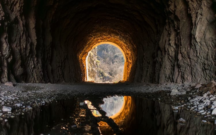 looking out of a mountain tunnel with light in the distance