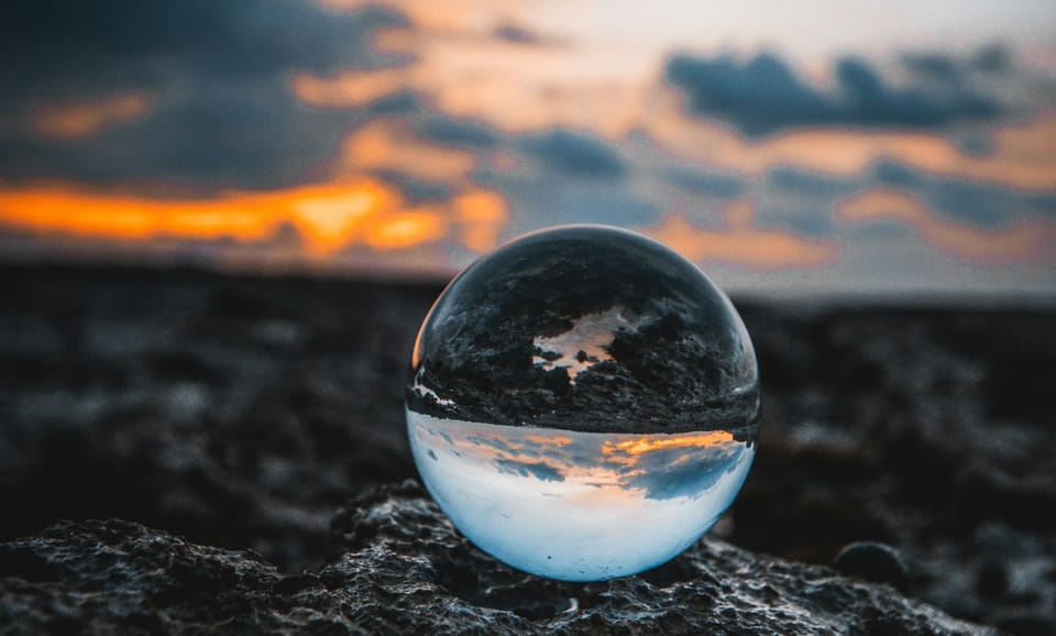 crystal sphere sitting on the ground reflecting earth and sky upside-down