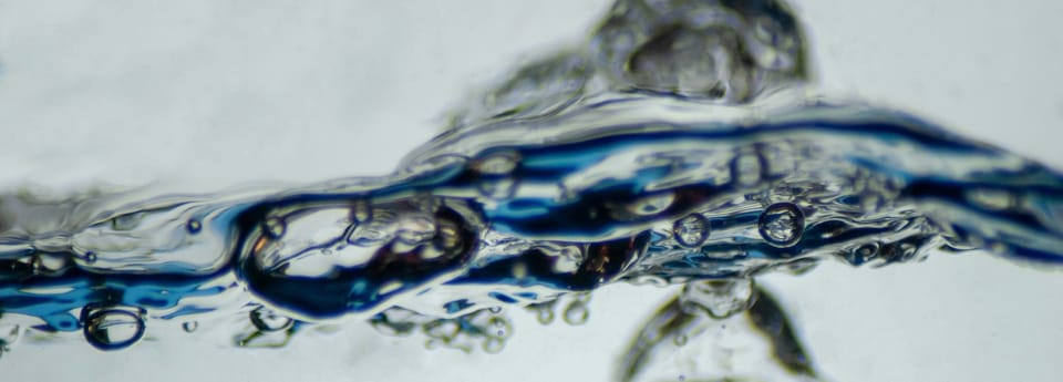 macro photo of elongated blue-tinted bubbles submerged in a clear liquid