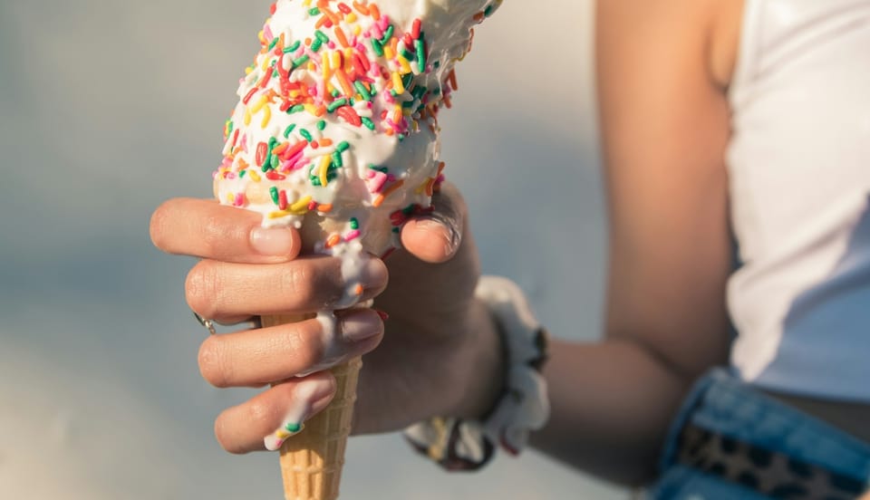 hand holding a melting ice cream cone on a sunny summer day