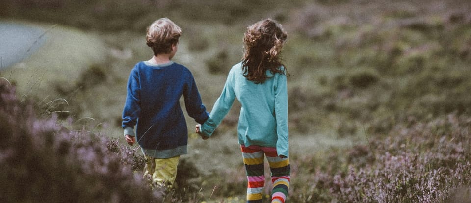 two children walking in a field